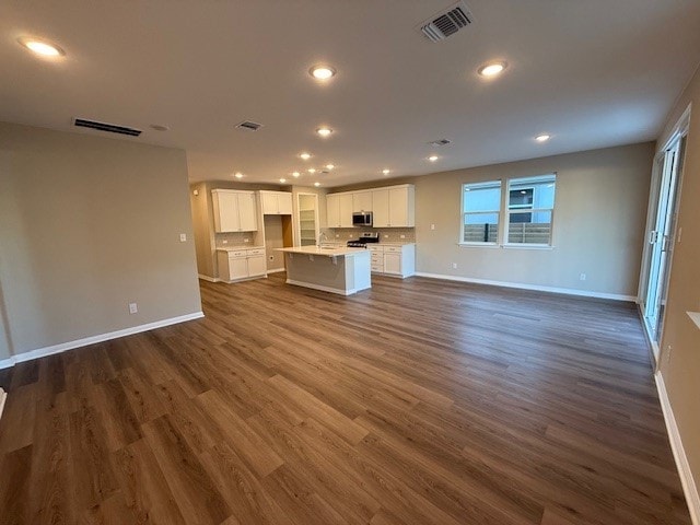 540 Raleigh Dr, Georgetown, TX 78633 - unfurnished living room featuring baseboards, recessed lighting, dark wood-style floors, and a sink