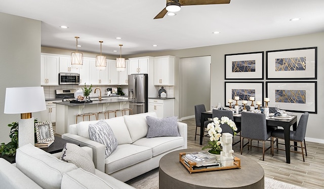 living room featuring ceiling fan, sink, and light hardwood / wood-style flooring