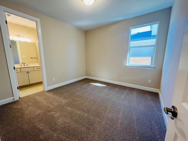 unfurnished bedroom featuring ensuite bath, sink, and carpet floors