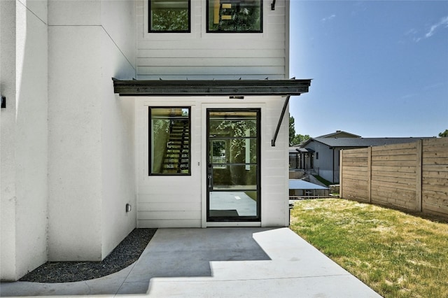 doorway to property featuring a patio, a yard, and fence