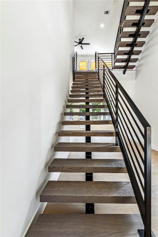 stairs featuring ceiling fan and hardwood / wood-style floors