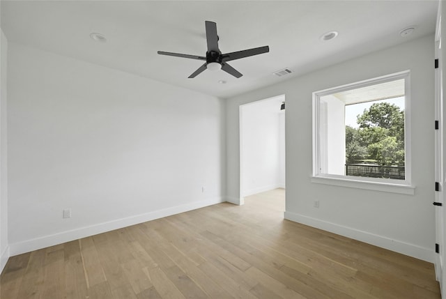 spare room featuring light wood-style floors, visible vents, ceiling fan, and baseboards