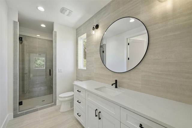 bathroom with an enclosed shower, tile walls, tile patterned floors, toilet, and vanity