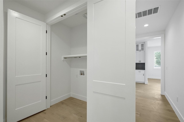 washroom with hookup for a washing machine, laundry area, visible vents, baseboards, and light wood-type flooring