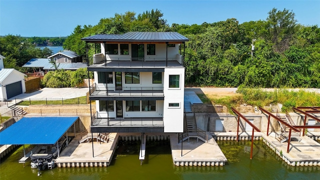 rear view of property featuring a balcony, a water view, and a patio area