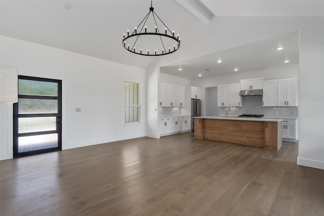 kitchen featuring beamed ceiling, an inviting chandelier, decorative backsplash, a kitchen island with sink, and dark hardwood / wood-style floors