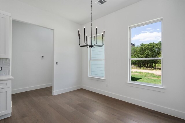 unfurnished dining area featuring dark wood-type flooring and a chandelier