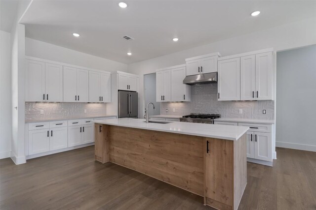 kitchen featuring stainless steel fridge, sink, backsplash, a kitchen island with sink, and wood-type flooring