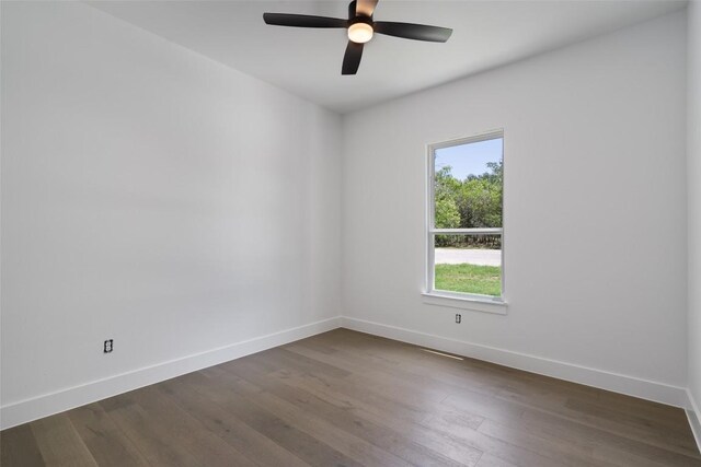 spare room featuring a healthy amount of sunlight, ceiling fan, and dark wood-type flooring