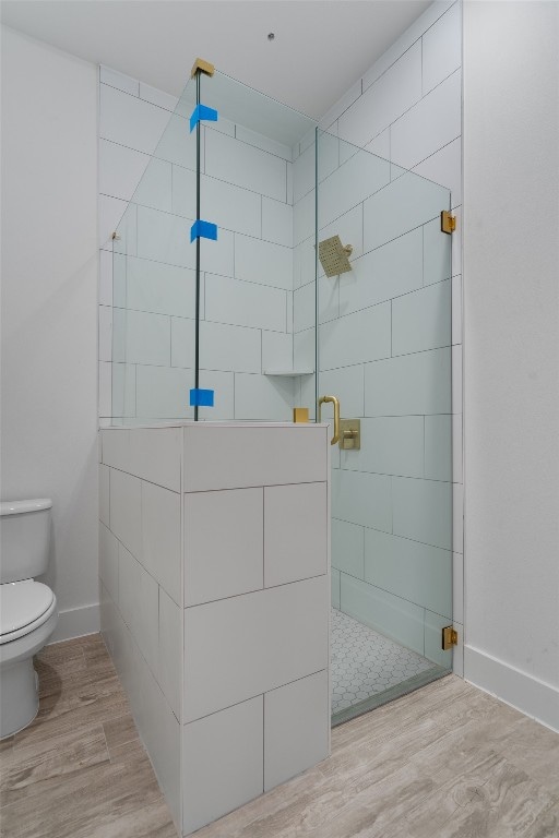 bathroom featuring a shower with door, hardwood / wood-style flooring, and toilet