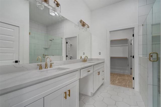 bathroom with a shower with shower door, wood-type flooring, and dual bowl vanity