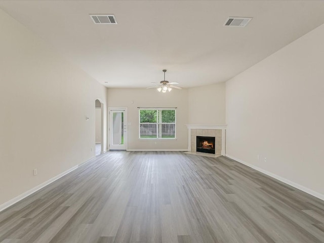 unfurnished living room with ceiling fan, a fireplace, and light hardwood / wood-style floors