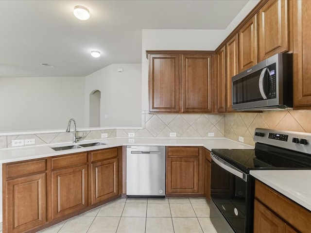 kitchen with stainless steel appliances, sink, light tile patterned floors, and decorative backsplash