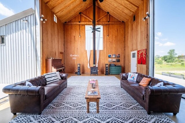 living room featuring high vaulted ceiling, ceiling fan, and wooden walls