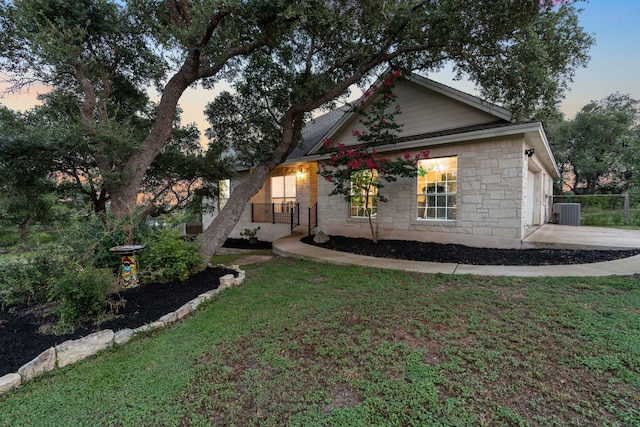 view of front of property with a lawn, a garage, and central AC unit