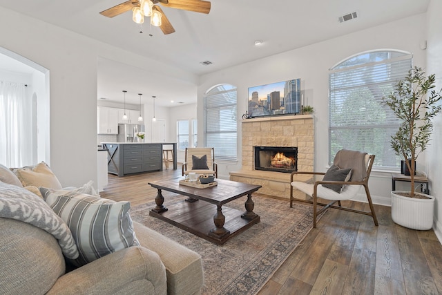 living room featuring a fireplace, ceiling fan, and dark wood-type flooring