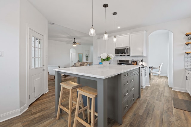 kitchen featuring a kitchen island, stainless steel appliances, white cabinetry, and decorative backsplash