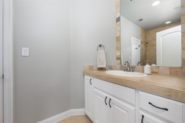 bathroom with tile patterned flooring, vanity, and tiled shower