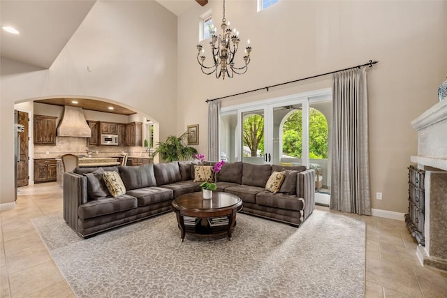 tiled living room featuring a towering ceiling and a notable chandelier