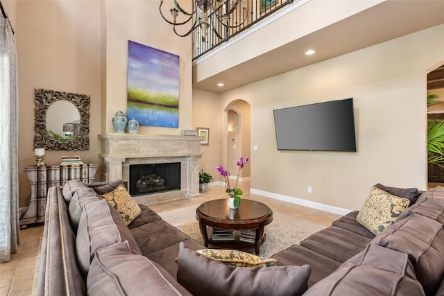 living room with a towering ceiling, a high end fireplace, a notable chandelier, and light tile patterned floors