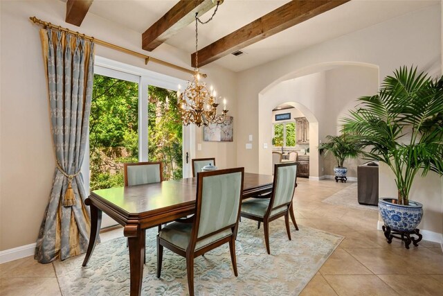 tiled dining space featuring an inviting chandelier and beamed ceiling