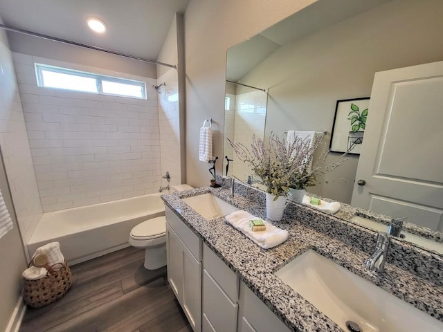 full bathroom with wood-type flooring, toilet, vanity, and tiled shower / bath