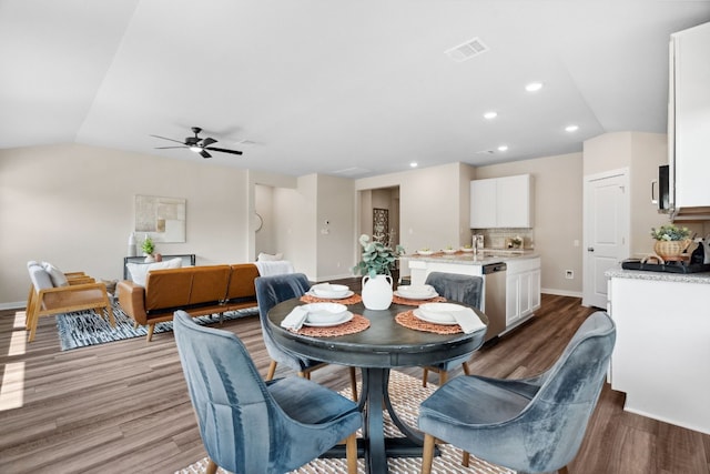 dining space with ceiling fan, wood-type flooring, sink, and vaulted ceiling