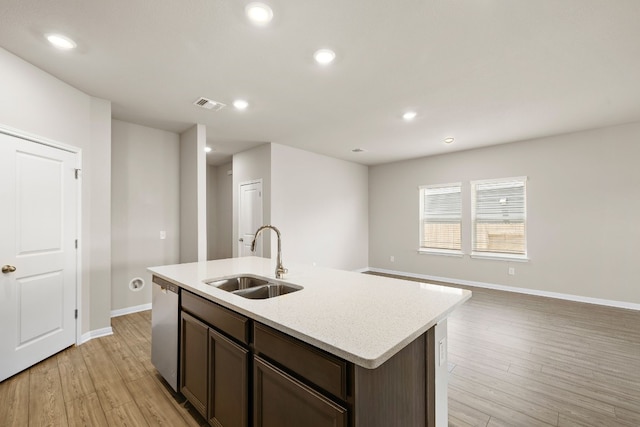 kitchen with sink, dark brown cabinetry, light hardwood / wood-style floors, dishwasher, and a center island with sink