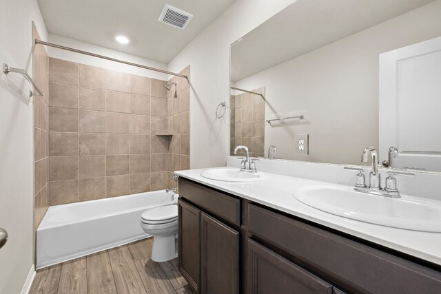 full bathroom with toilet, vanity, tiled shower / bath combo, and wood-type flooring