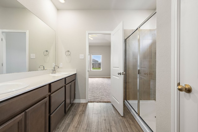 bathroom with walk in shower, vanity, and wood-type flooring