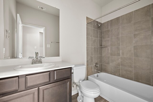 full bathroom with toilet, hardwood / wood-style floors, tiled shower / bath combo, and vanity