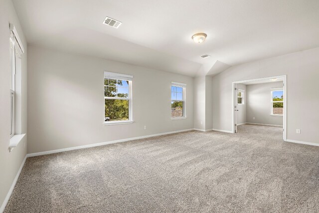 carpeted spare room featuring vaulted ceiling