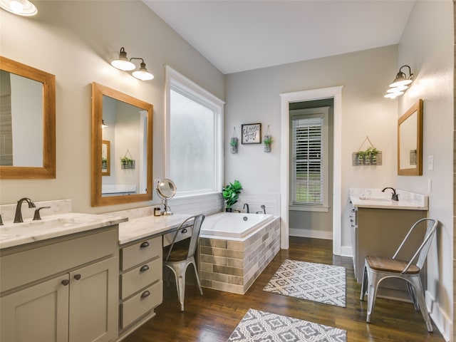 bathroom featuring hardwood / wood-style floors, vanity, and a relaxing tiled tub