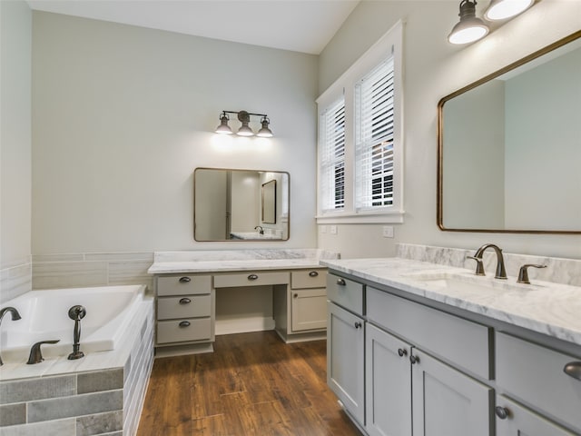 bathroom featuring tiled tub, vanity, and hardwood / wood-style flooring