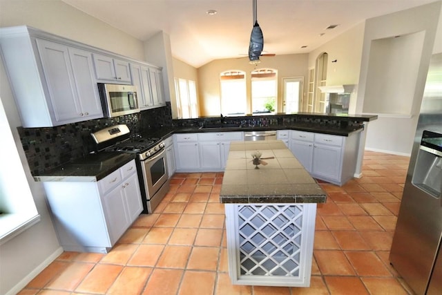 kitchen with white cabinetry, hanging light fixtures, stainless steel appliances, lofted ceiling, and a kitchen island