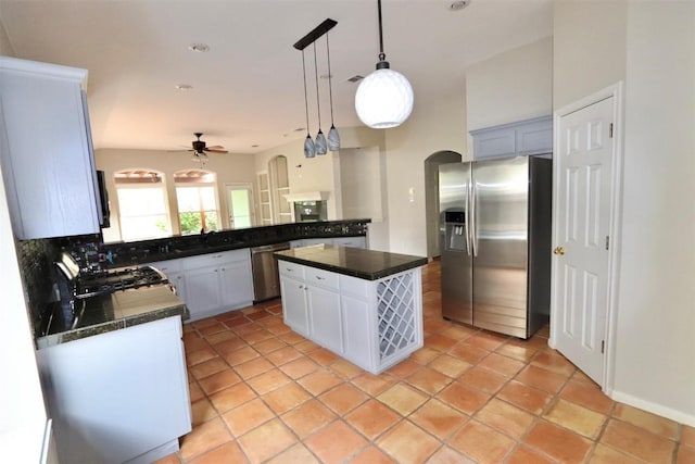 kitchen featuring pendant lighting, a center island, ceiling fan, decorative backsplash, and stainless steel appliances