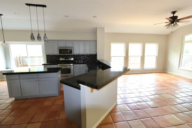 kitchen with kitchen peninsula, decorative light fixtures, stainless steel appliances, and a healthy amount of sunlight