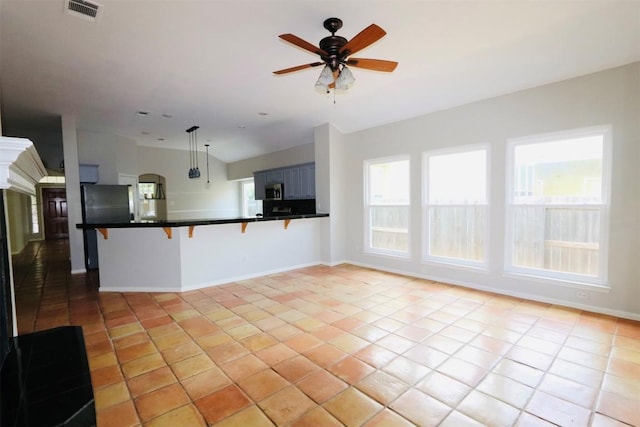 kitchen featuring decorative light fixtures, light tile patterned flooring, a kitchen bar, and kitchen peninsula