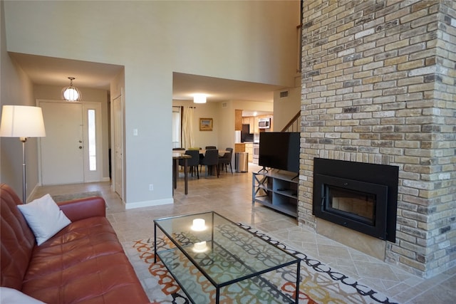 living room featuring a brick fireplace and light tile patterned floors