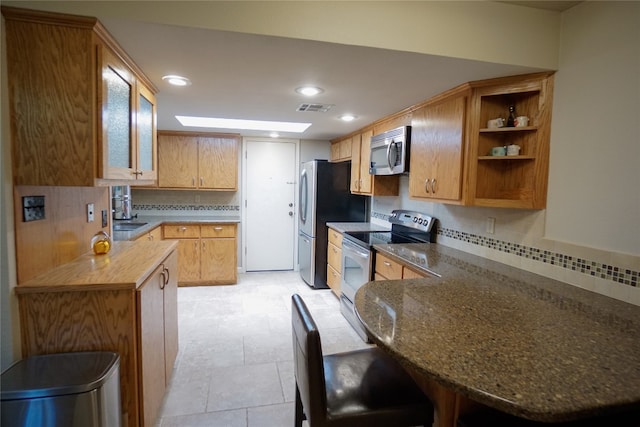 kitchen with kitchen peninsula, appliances with stainless steel finishes, decorative backsplash, and wood counters