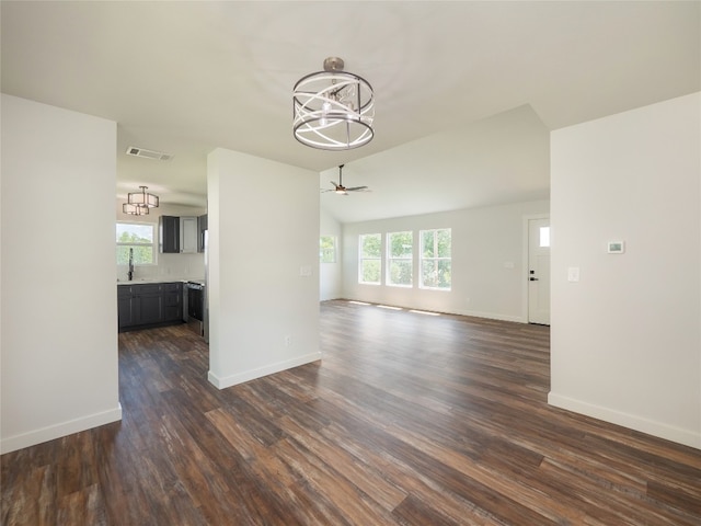 unfurnished living room with ceiling fan with notable chandelier, dark hardwood / wood-style floors, sink, and a wealth of natural light