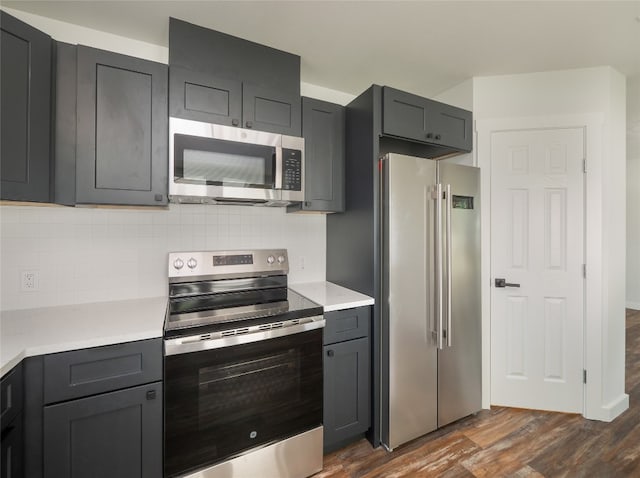 kitchen featuring stainless steel appliances, dark wood-type flooring, and tasteful backsplash