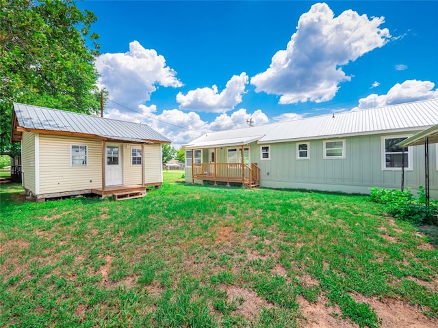 back of property featuring a lawn, an outdoor structure, and a wooden deck