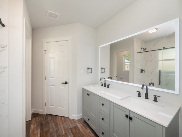 bathroom with a tile shower, hardwood / wood-style flooring, and vanity