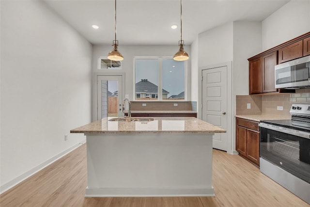 kitchen with sink, light stone counters, hanging light fixtures, appliances with stainless steel finishes, and decorative backsplash