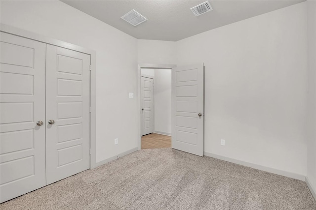 unfurnished bedroom with a closet and light carpet