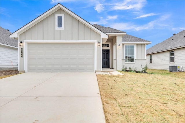 view of front facade with a garage, central AC, and a front lawn