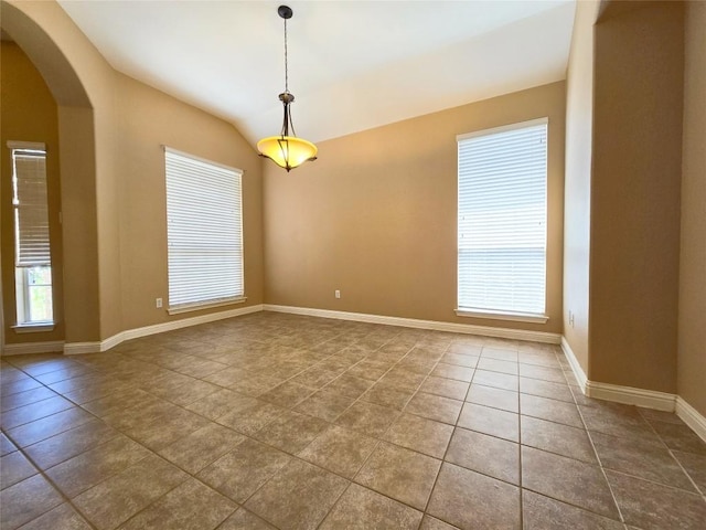 tiled spare room with vaulted ceiling