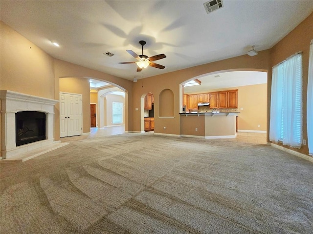 unfurnished living room with ceiling fan and light colored carpet