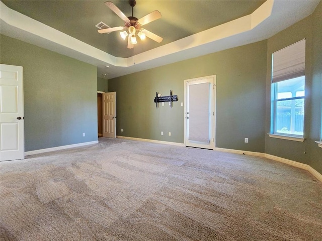 spare room with a tray ceiling, carpet flooring, and ceiling fan